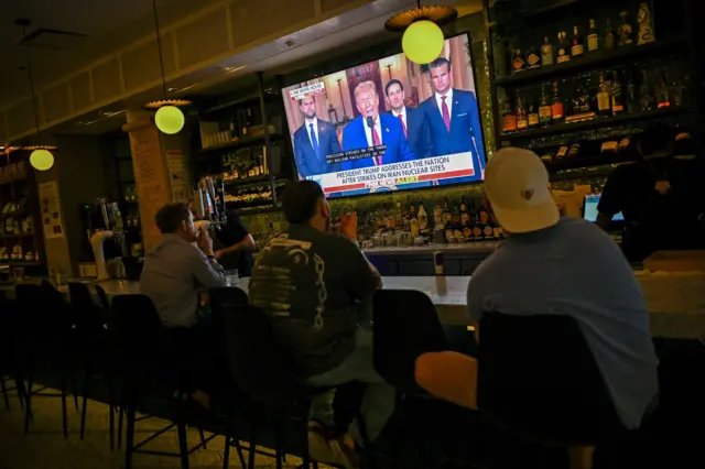 Personas en un bar en Chicago ven el anuncio de Trump por televisión.