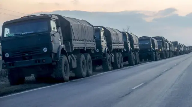 Una fila de camiones militares rusos circulando por una carretera.