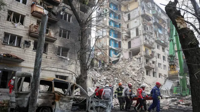 Imagen de socorristas transportando un cadáver en el lugar donde se encontraba un edificio de apartamentos en Kiev.