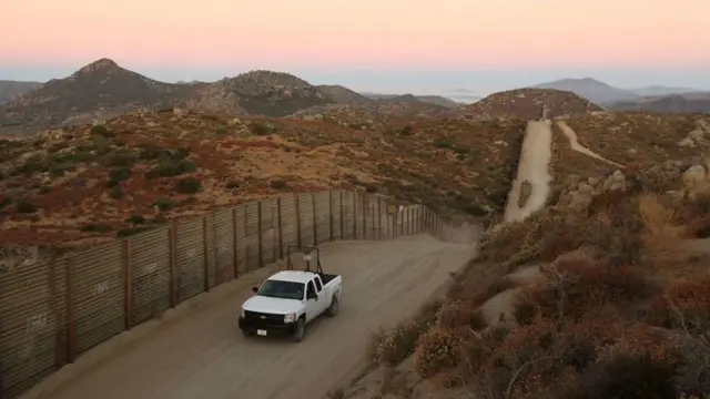 Un vehículo de la patrulla policial circula cerca del muro que divide la frontera entre México y EE.UU.