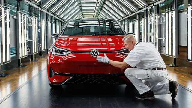 Un operario limpia un carro Volkswagen rojo con una gamuza antes de que abandone la fábrica