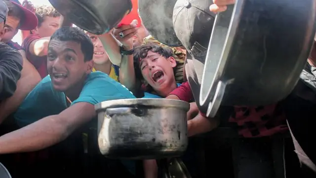 Niños y adolescentes apilados con ollas vacías luchan por obtener un plato de comida en una cocina popular