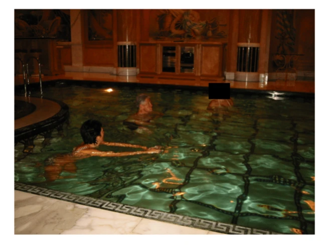 Un hombre que parece ser Bill Clinton, con dos mujeres en una piscina en el interior de un edificio. 