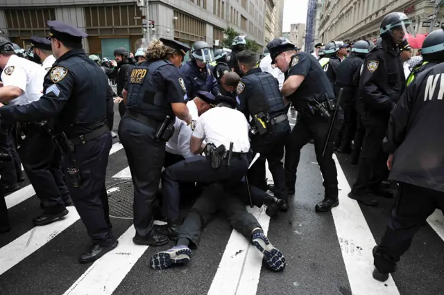 Un grupo de policía está inmovilizando a un manifestante en el piso en las calles de Nueva York.
