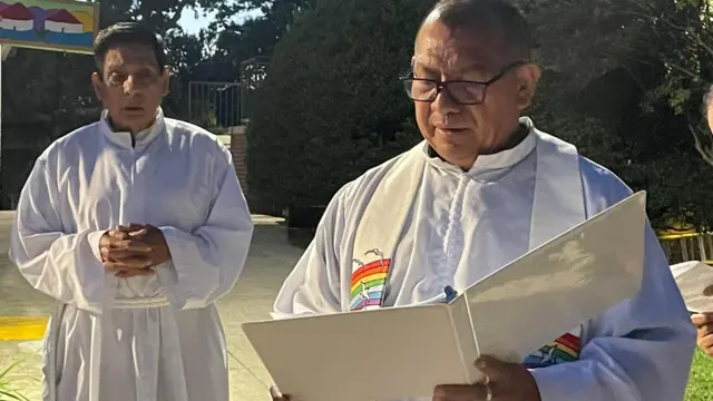 El padre Vidal Rivas (derecha), párroco de San Mateo, en Hyattsville, Maryland, lee durante en festival de San Francisco de Asís junto a otro sacerdote.