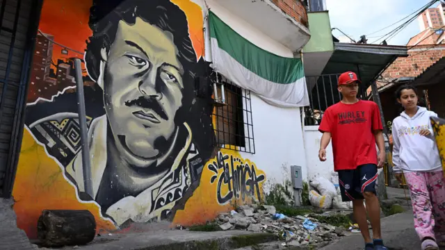 Niños caminando junto a un mural de Pablo Escobar en Medellín en 2023.