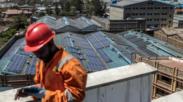 Un técnico trabaja en la instalación de paneles solares en el tejado de una fábrica parcialmente alimentada con energía solar en la zona industrial de Nairobi.