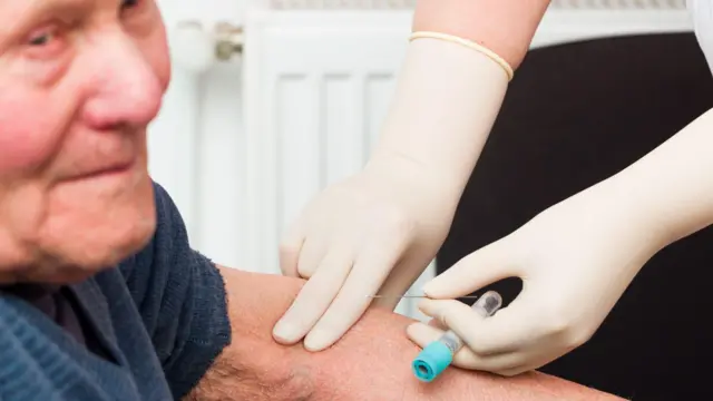 una persona tomando una muestra de sangre a un adulto mayor 