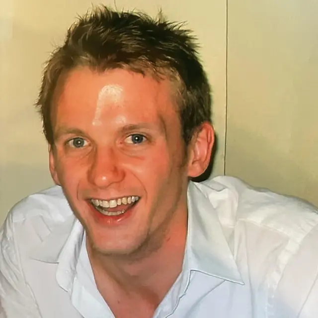 Foto de James sonriendo y vistiendo una camisa blanca.