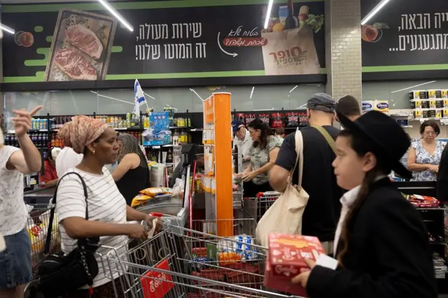 Varias personas en un supermercado con productos