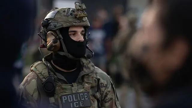 Agente de ICE con uniforme de camuflaje y la cara parcialmente tapada