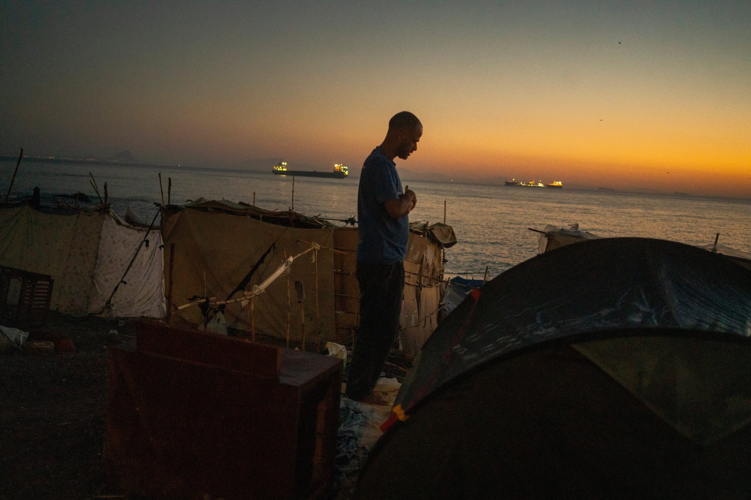 Un hombre reza al amanecer en la playa del Trampolín.