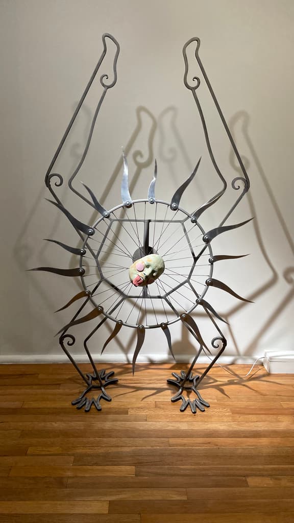 Escultura de metal con una máscara que gira del artista francés Antoine Granier.
