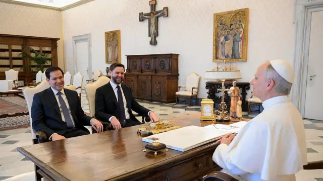 El papa León XIV se reúne con el vicepresidente estadounidense JD Vance y el secretario de Estado estadounidense Marco Rubio el 19 de mayo de 2025 en la Ciudad del Vaticano. Ambos están sentados frente a él, separados por el escritorio del papa. El papa viste su tradicional túnica blanca, mientras que Rubio y Vance llevan traje.