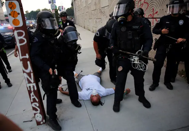 Personas permanece en el suelo rodeado de agentes de seguridad en el centro de Los Angeles