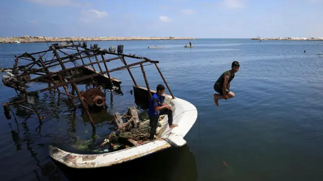 Una fotografía de niños palestinos en la Franja de Gaza saltando desde un barco naufragado al mar.