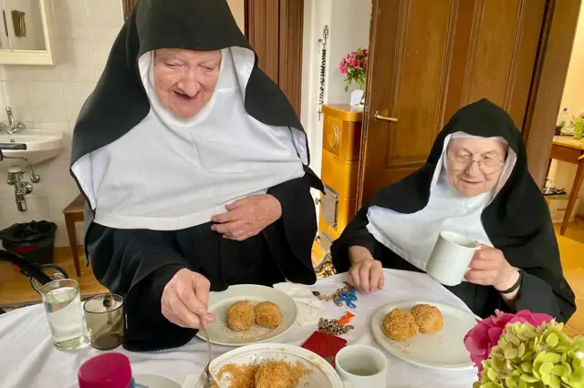 Una monja le sirve a otra algo de comer.