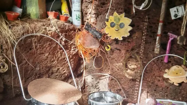 Foto del interior de la cueva en la que vivía la familia de Nina Kutina. En un pequeño hueco junto a las raíces de un árbol se distinguen varios recipientes de metal y varios adornos.