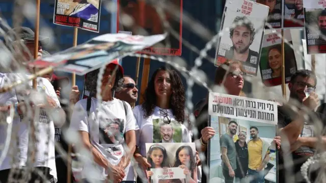 Familias de rehenes israelíes sosteniendo sus fotos en una manifestación para exigir su liberación.