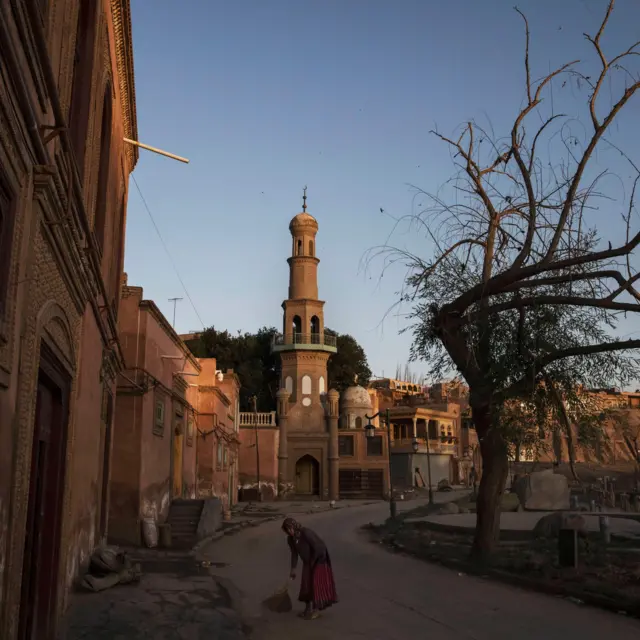 En esta fotografía tomada en 2017, una mujer uigur barre la puerta de su casa en el casco antiguo de Kasgar.