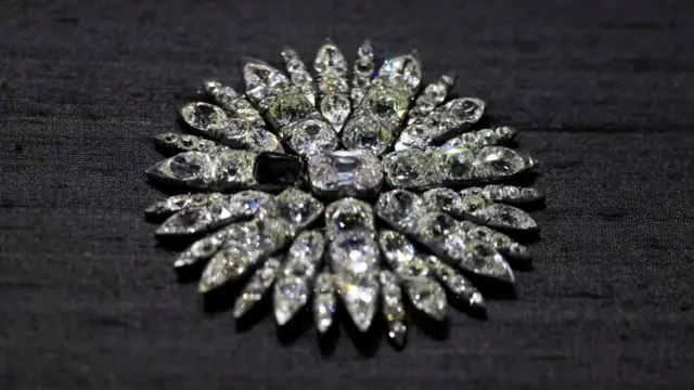 Un deslumbrante accesorio con incrustaciones de diamantes en forma de sol sobre un fondo negro. Una pieza faltante destaca en el centro del artículo.