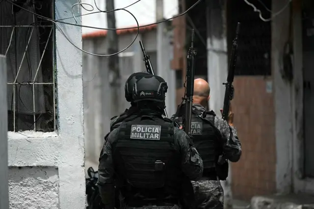 Dos policías militares uniformados y armados hacen una incursión en una favela de Río de Janeiro.