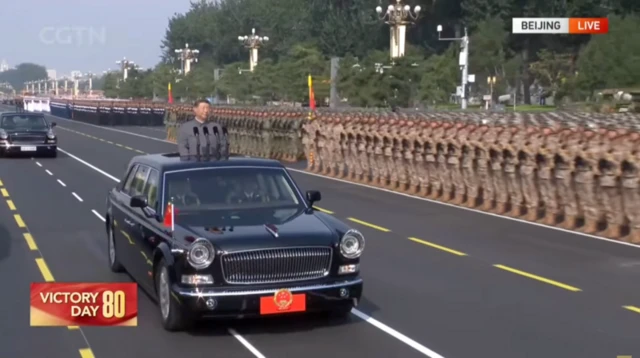 Xi Jinping por fuera de un auto en una carretera con numerosos soldados a un lado