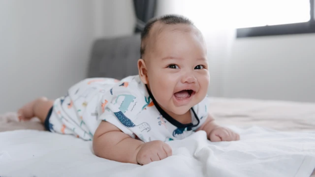 Un bebé sonriente tumbado sobre su barriga. 