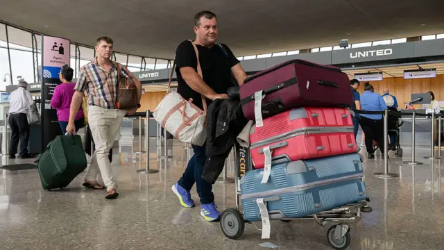 Charl Kleinhaus llegando al aeropuerto y empujando un carro con 3 maletas muy grandes.