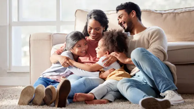 Familia feliz con dos hijas abrazando a su madre y creando vínculos en casa.