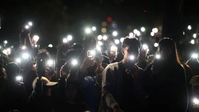 Un grupo de espectadores ilumina con las linternas de sus teléfonos móviles durante un homenaje a las víctimas del ataque terrorista de Bondi, durante las celebraciones de Nochevieja en Mrs Macquaries Point, en Sídney, Australia.