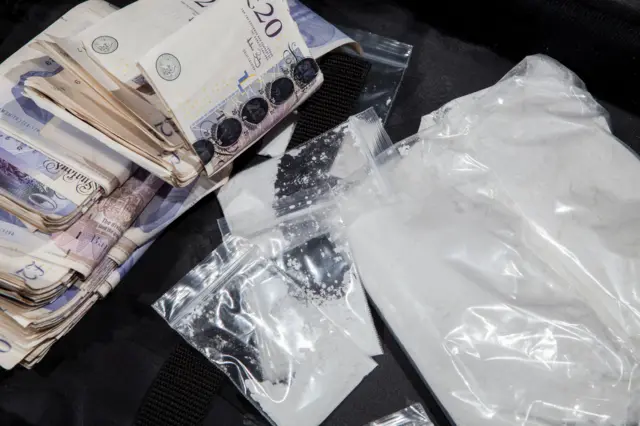 Sobres con una sustancia que simula ser cocaína junto a un fajo de billetes de 20 libras esterlinas.