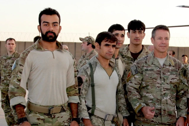 Safi de pie en fila junto a sus compañeros militares en Estados Unidos. Lleva un uniforme de médico militar y está de pie, con aire desenfadado, junto a otros cuatro médicos militares.