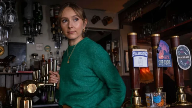 Una mujer observa detrás de la barra de un bar. 