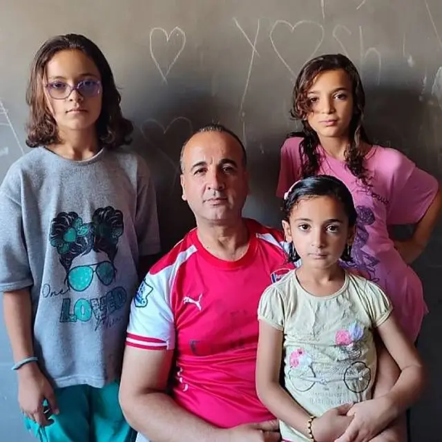  Alathamna con tres de sus hijos, todos miran fijamente a la cámara.