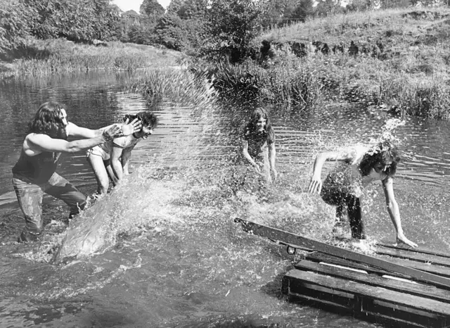 Una fotografía en blanco y negro que muestra a los miembros de Black Sabbath chapoteando en el río en el pintoresco valle de Wye, 1977.