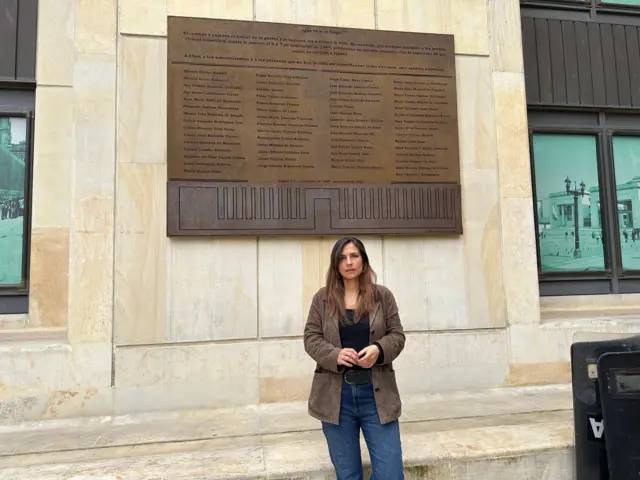 Helena Uran, hija del magistrado Carlos Horacio Uran, frente a la tarjeta de reconocimiento a víctimas en el patio interior del Palacio de Justicia.