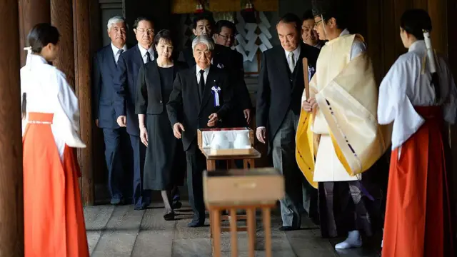 Un grupo de parlamentarios vestidos con trajes oscuros y otras personas con trajes tradicionales de Japón
