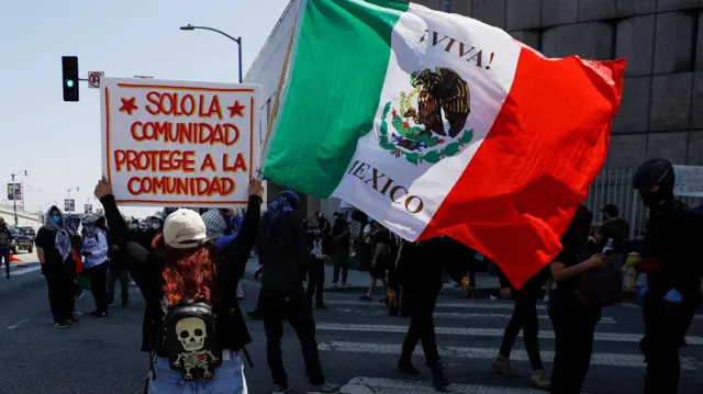 Una manifestante sostiene una bandera mexicana y un cartel que dice 'solo la comunidad protege a la comunidad', durante una protesta contra las redadas federales de inmigración, tras el despliegue de miembros de la Guardia Nacional de California fuera del edificio federal Edward R. Roybal por el presidente de EE. UU. Donald Trump en respuesta a las protestas, en Los Ángeles, California, EE. UU., 8 de junio de 2025. REUTERS/Mike Blake