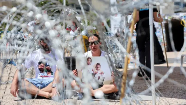 Lishay Lavi, mujer del rehén Omri Miran, secuestrado por Hamás, sentada entre alambradas junto a un hombre en una protesta en Tel Aviv.