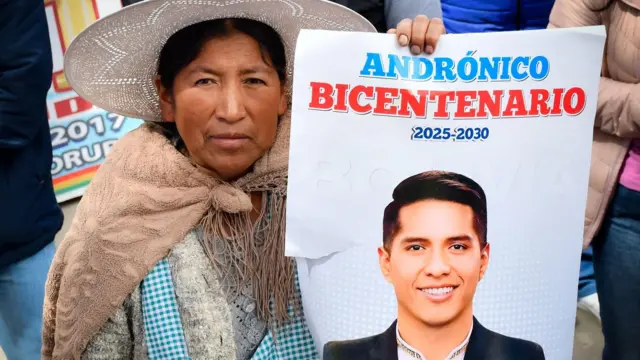Una mujer sostiene un afiche con la cara de Andrónico Rodríguez.