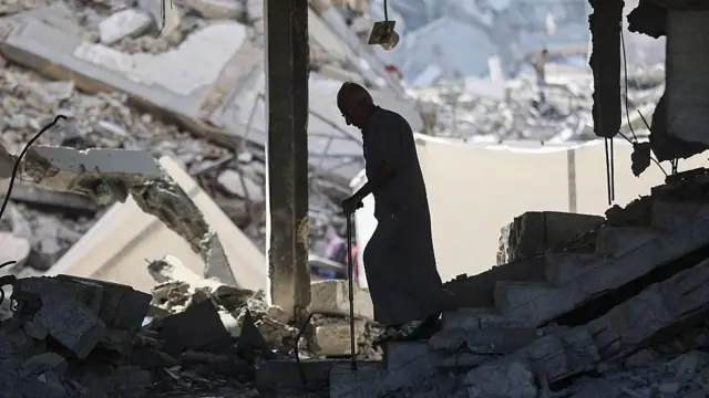 Un anciano con bastón camina entre las ruinas de la ciudad de Gaza.