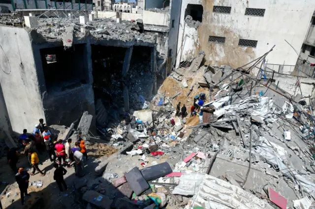 Palestinos buscan supervivientes entre los escombros de un edificio destruido por un ataque aéreo israelí.