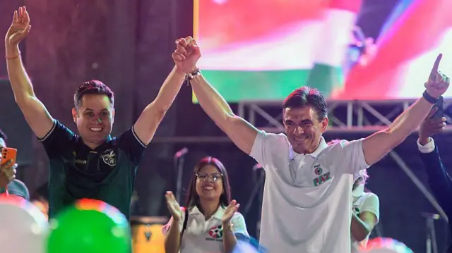 La fórmula presidencial Rodrigo Paz y Edmand Lara celebran sobre un escenario  con los brazos arriba