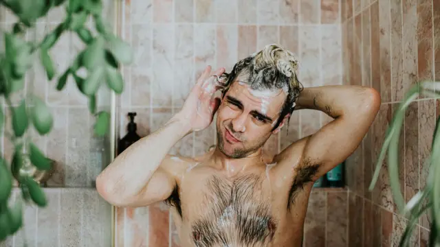 Hombre enjabonándose en la ducha