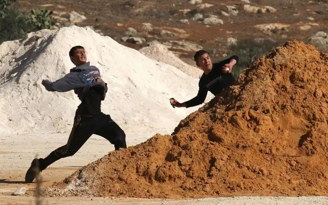 Dos niños tiran piedras.