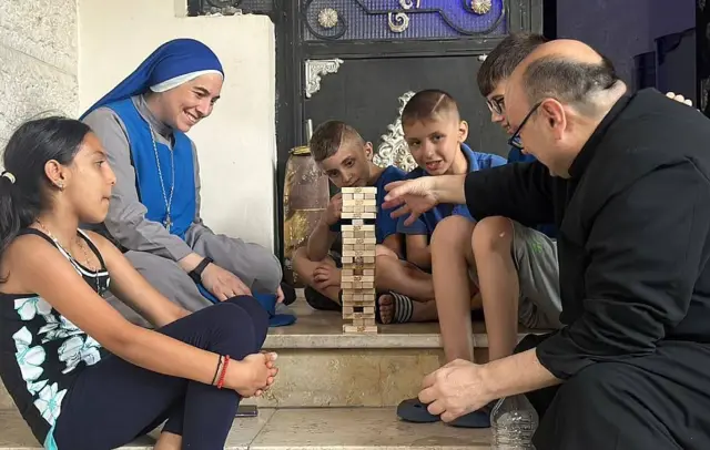 El padre Gabriel y la hermana María de las Maravillas de Jesús jugando con niños