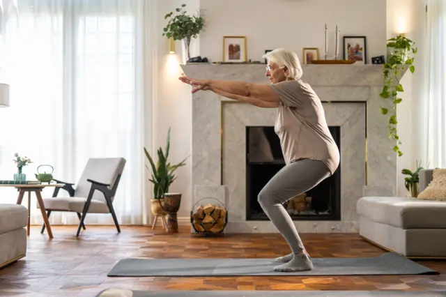 Una mujer mayor haciendo ejercicio en su sala