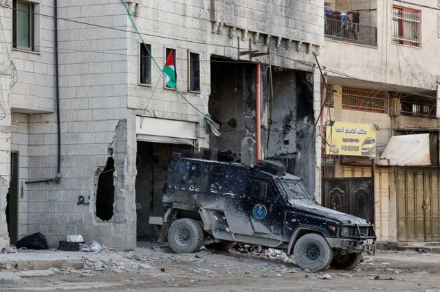 Un vehículo de las fuerzas de seguridad palestinas en un edificio dañado