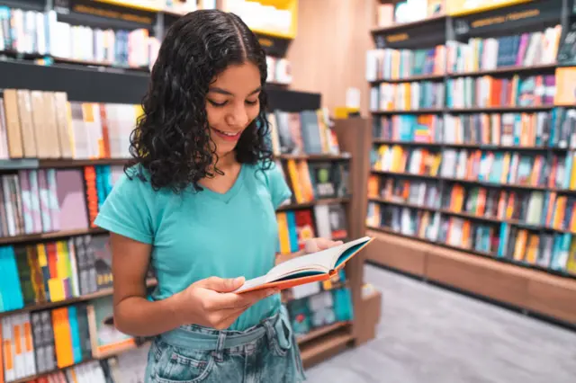 Una niña leyendo un libro en una biblioteca